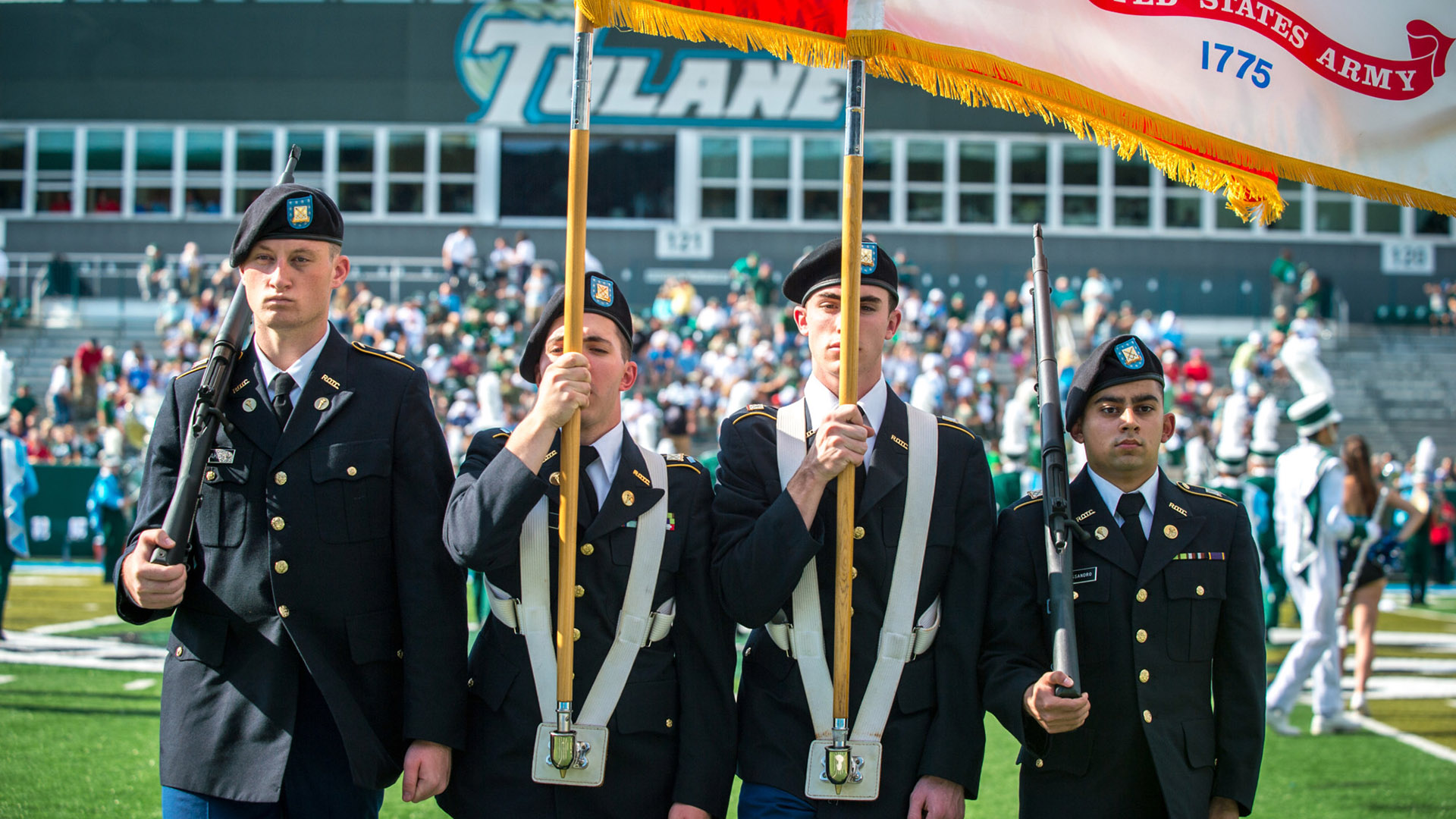  Members of the ROTC at Tulane carry flags and rifles on the field.